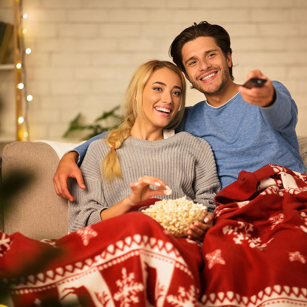 Couple watching holiday movie on upholstered sofa, upholstery cleaning 20% off